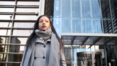 latin business woman posing against an office building in the financial district.