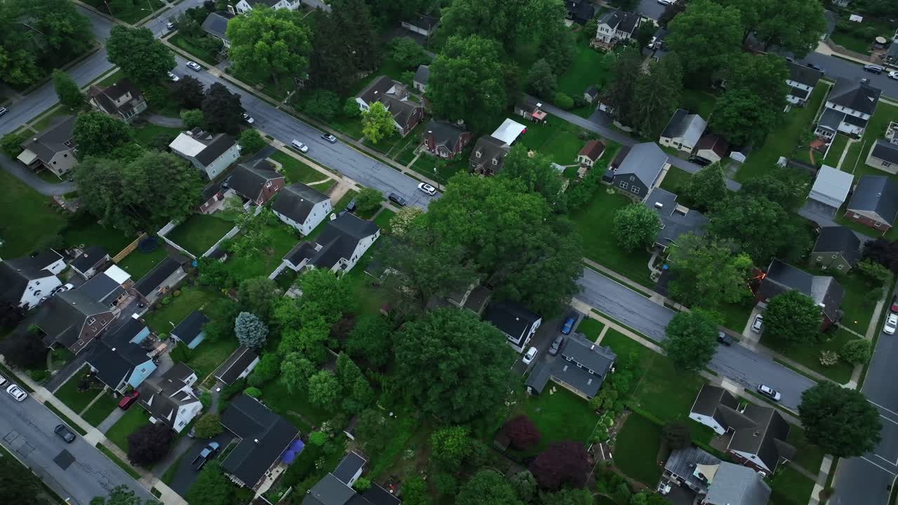 Row of houses with small garden in suburb neighborhood of city. American suburbia with one family houses at cloudy summer day. Aerial top down shot. Serene atmosphere flight