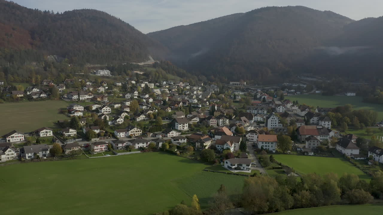 Luchtfoto van een dorp op het platteland, omringd door mistige bergen