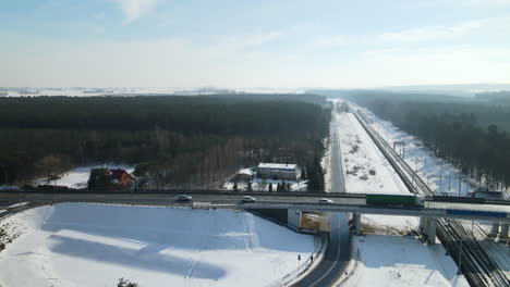 Fahrzeuge,-Die-An-Der-Brücke-über-Die-Leere-Eisenbahn-In-Rakowice,-Krakau,-Polen-Mit-Schneebedeckter-Stadtlandschaft-Im-Winter-Vorbeifahren