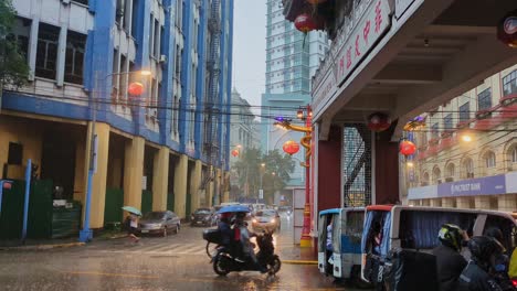 static shot of busy streets and buildings at binondo chinatown entrance, manila during rainy day.