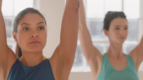 clase de yoga mujer de raza mixta saludable practicando pose de guerrero disfrutando de un estilo de vida físico haciendo ejercicio con personas multiétnicas en un estudio de entrenamiento