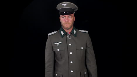 german second world war wehrmacht army officer in grey uniform pointing p38 pistol gun at the camera with black background