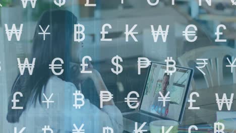 animation of currency symbols over biracial woman having video call on laptop