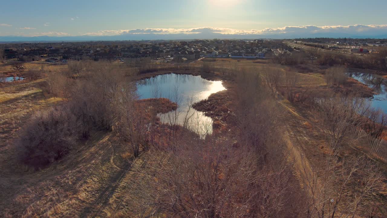 This short left pan shows one of the many parks in Greeley Colorado along with the urban cityscape and the rocky mountains in the distance