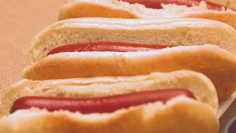 Close-up-of-a-plate-of-delicious-hot-dogs-with-a-selection-of-toppings-on-the-side