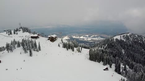 aerial view over poiana brasov ski resort, covered in a thick layer of snow, with skiers going down the slope, romania