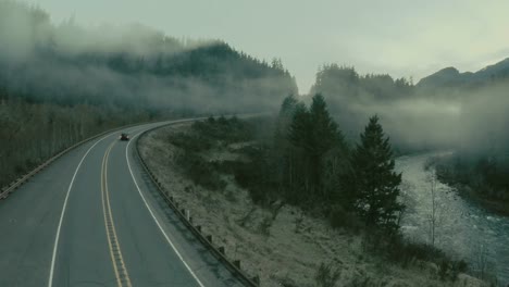 car trip on misty foggy highway between river and forest