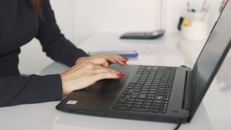 Primer-Plano-De-Manos-Femeninas-Trabajando-En-Una-Computadora-Portátil-En-El-Fondo-De-La-Oficina