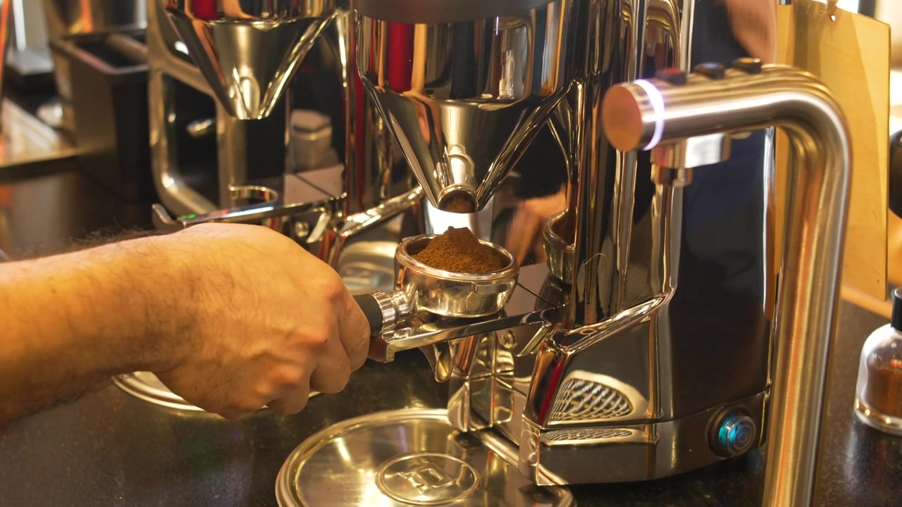 Processo professionale di macinatura del caffè con barista che dosa il caffè macinato nel portafiltro in un caffè moderno