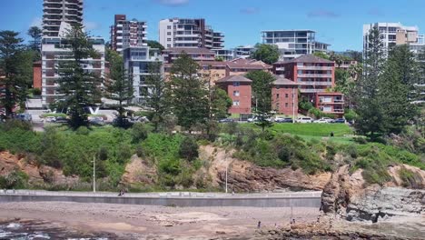 Aerial-tilt-up-from-the-rocks-and-surf-to-the-high-rise-buildings-of-Wollongong-in-the-background