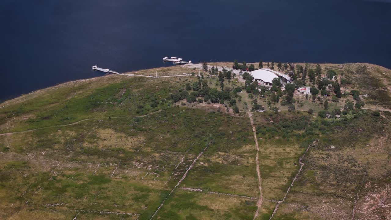 Panoramic aerial drone footage of the Calles Dam island featuring the iconic Cristo Roto sculpture in San José de Gracia, Mexico. Scenic views of water, landscape, and cultural landmark