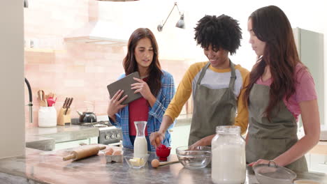 women friends baking together in kitchen, laughing and enjoying holiday preparations