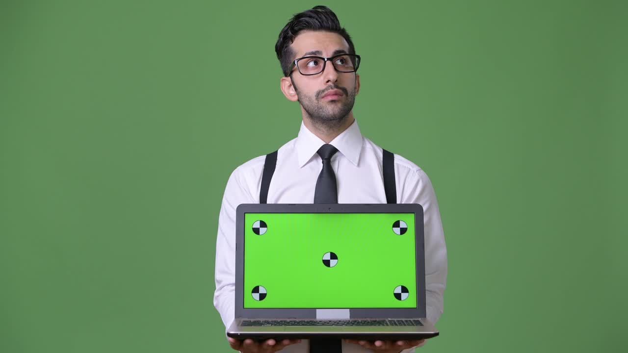 joven empresario persa barbudo y guapo contra un fondo verde