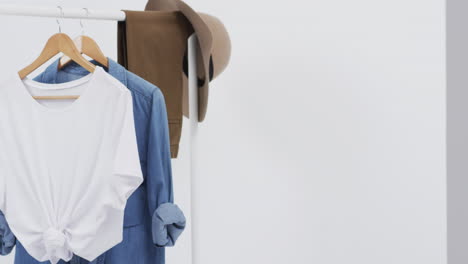 video de camiseta blanca y denim en perchas, sombrero y espacio de copia sobre fondo blanco