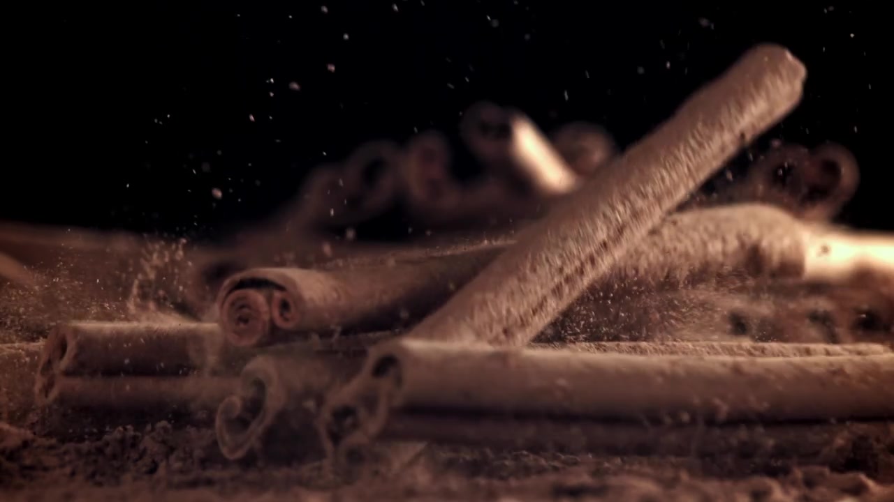 Kanelstenger faller ned på malt kanel i sakte film