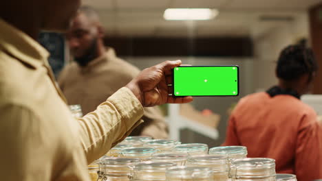 african american seller shows greenscreen display on mobile phone