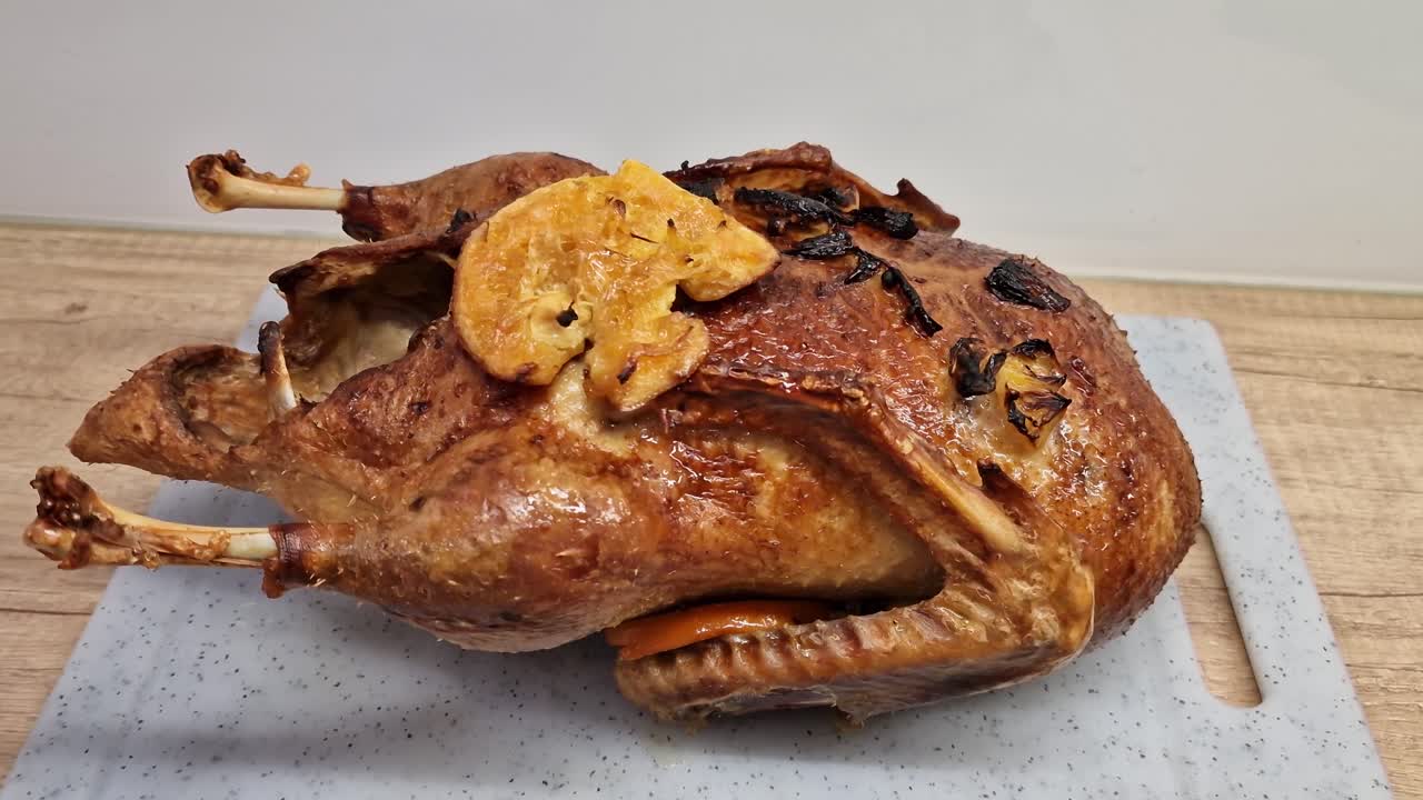 Whole roasted duck with crispy golden skin on a cutting board. Gourmet festive poultry dish prepared with orange and spices. French cuisine Canard à l'Orange ready for serving