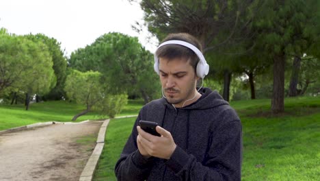 man puts on headphones, uses the phone and starts running