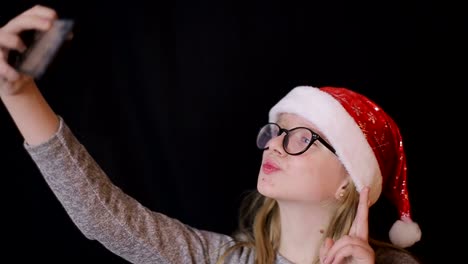 teenage blonde girl taking selfie with smartphone in her pink room shot of young teenage blonde girl in pink outfit taking selfie with smartphone while sitting on bed in her room