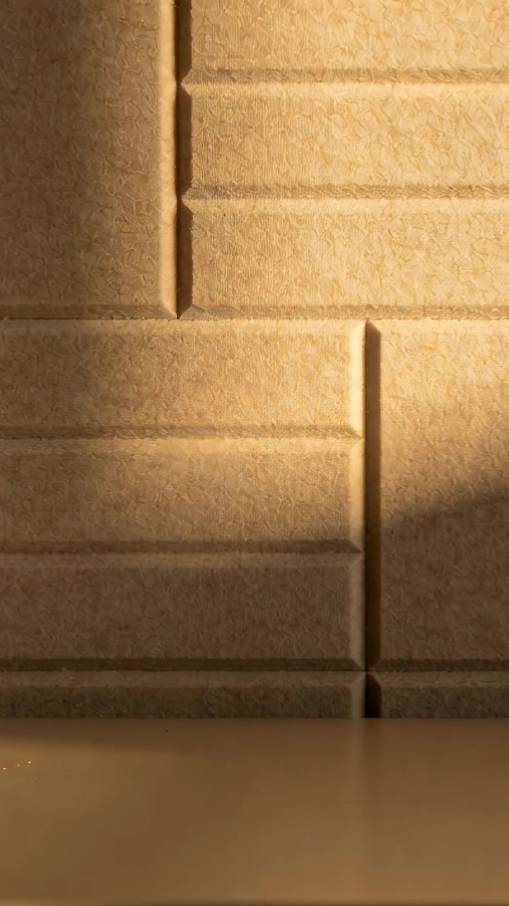 Vídeo vertical: Luz solar quente se deslocando da direita, projetando sombra sobre painéis com prateleira em um ambiente.