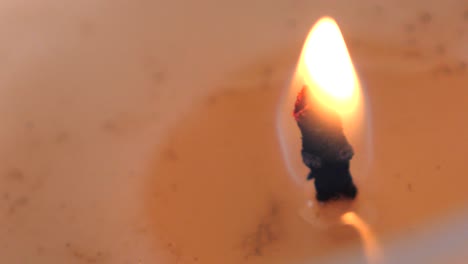 slow motion macro footage of orange candle flame burning and flickering surrounded by soy wax