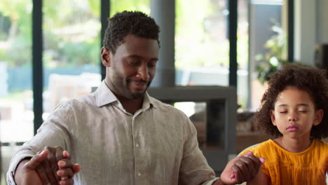 Close-Up-Of-Multi-Generation-Family-Joining-Hands-And-Saying-Prayer-Before-Meal-At-Home