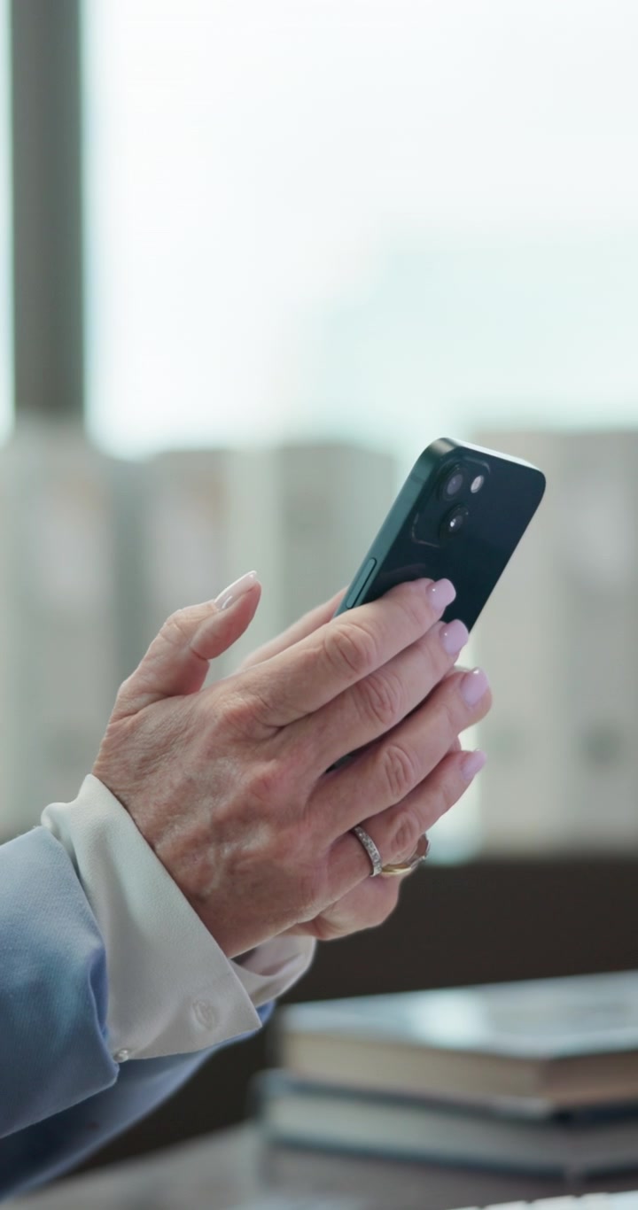 Primo piano di una donna anziana che utilizza uno smartphone in ufficio