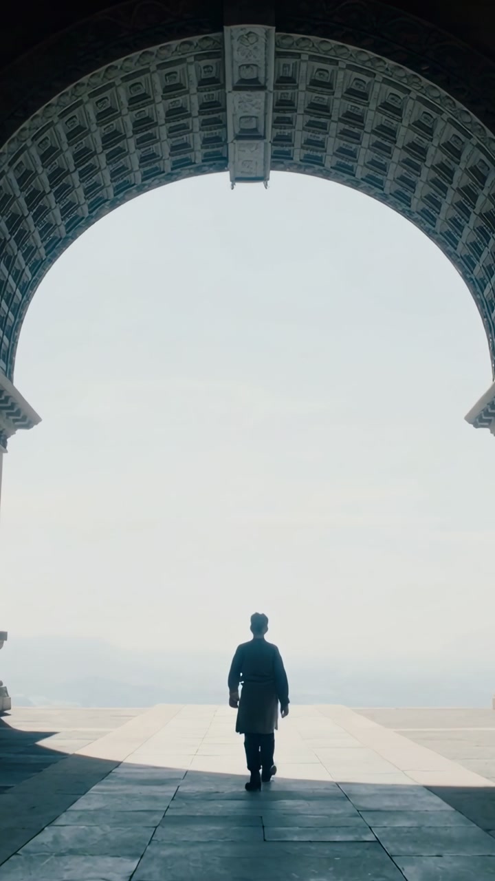 Person Walking Through a Grand Archway Towards a Bright Horizon