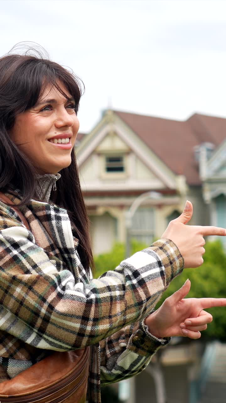 Mujer joven feliz señalando casas victorianas en San Francisco