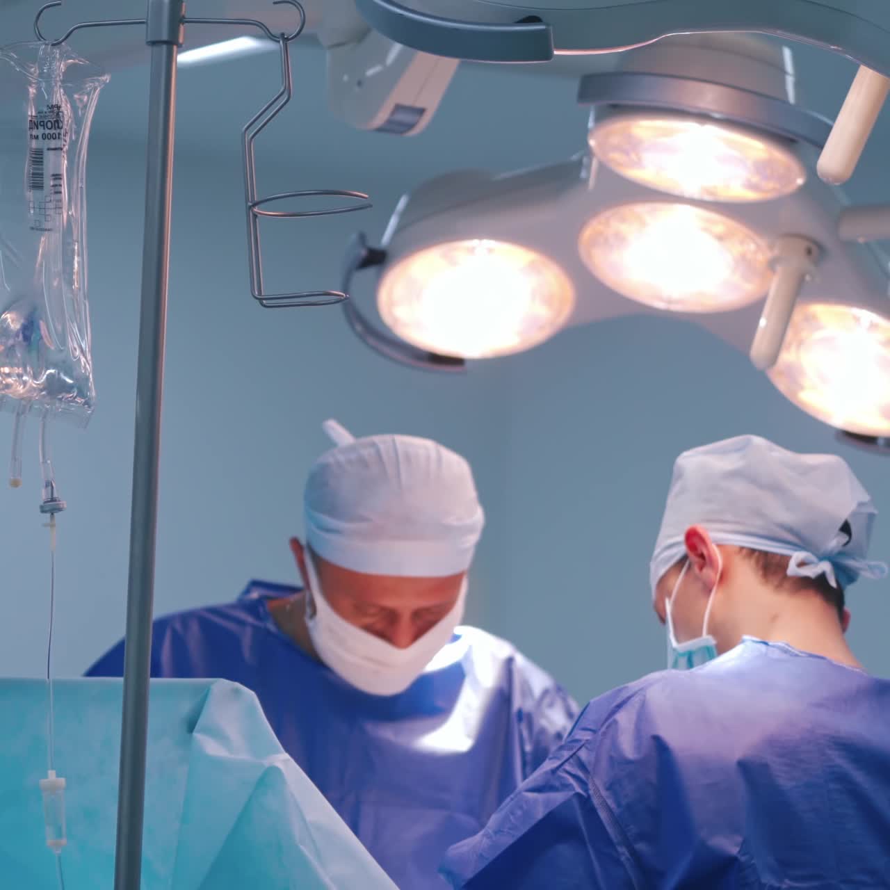 Surgeons in medical uniform doing a surgery. Bright lamp over the operating theatre in the modern clinic. Healthcare concept.