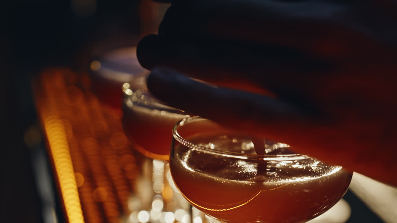 Primo piano di un barista che versa un cocktail in coppette da cocktail. Mano che filtra il liquido