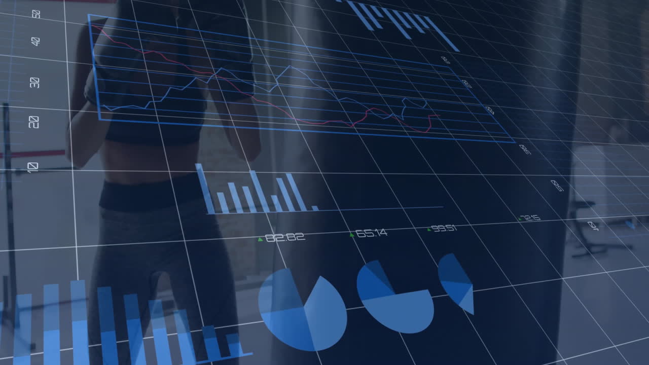 Fitness enthusiast practicing punching bag in gym showing digital line and bar charts and pie chart