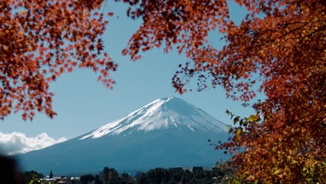 captivating footage of mount fuji towering over lake kawaguchiko, framed by vibrant red autumn foliage.