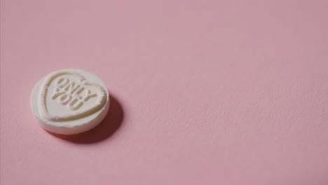 Hand-Picking-Up-Heart-Candy-With-Romantic-Message-Only-You-On-Pink-Background