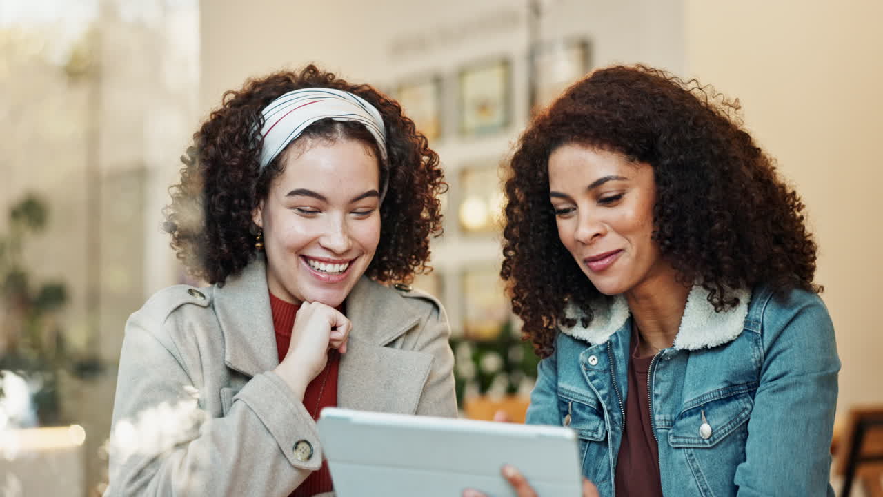 Two friends sharing a laugh while looking at a tablet