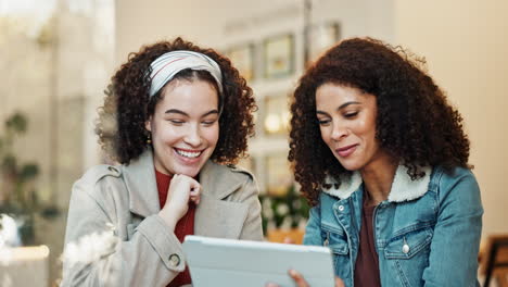 two friends sharing a laugh while looking at a tablet