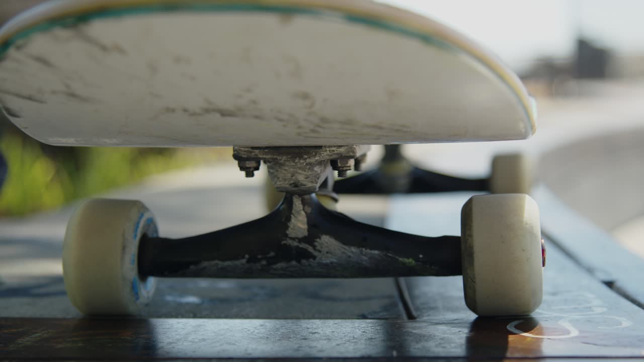 Smooth panning shot of a skateboard resting on a concrete ledge at the skatepark
