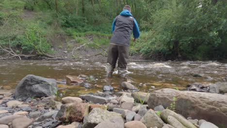 Toma-Estática-Baja-De-Un-Hombre-Vadeando-Y-Pescando-Con-Mosca-En-Un-Pequeño-Río-Aislado-En-Escocia