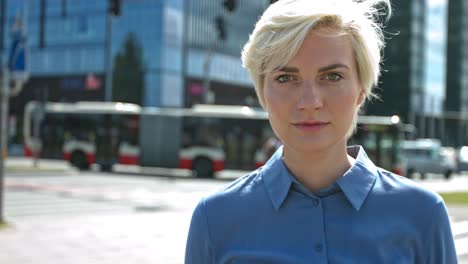 a business woman stands in the city center in the business district and looks at the camera