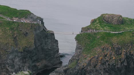 Panorámica-Descendente-Del-Puente-Colgante-De-Carrick-a-Rede-Y-Una-Isla-Distante