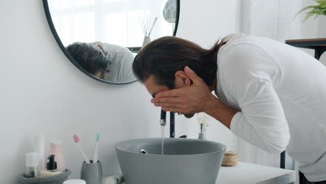 man washing face and grooming in bathroom