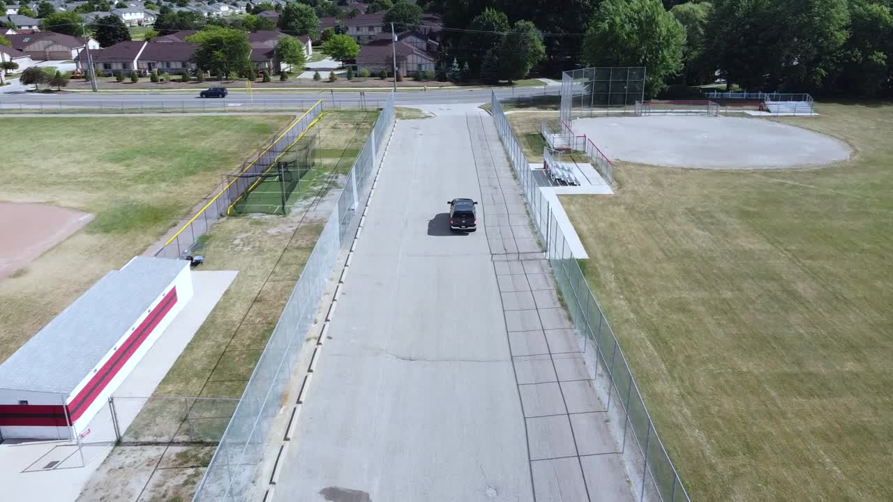 A mavic mini tracks a new truck from a parking lot down a side street.