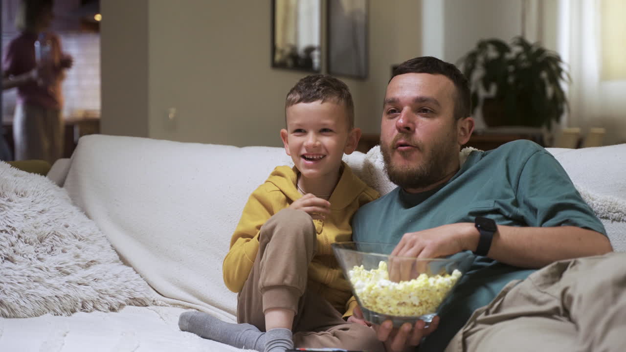 Famiglia seduta sul divano che guarda un film.