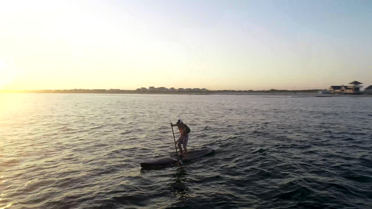 Paddleboarder paddling away into the sunset.