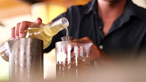 bartender pouring alcohol into a glass cocktail stirrer at a bar in the caribbean