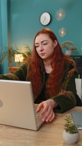 woman sitting at table closing laptop pc after finishing online distant work at home office room