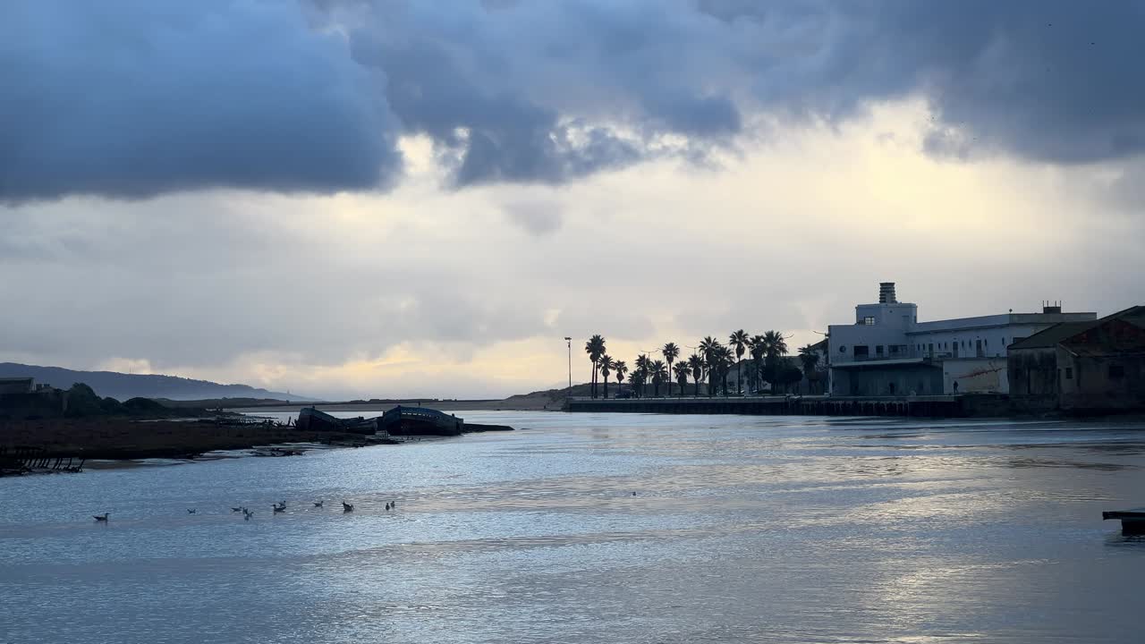 Flot, bredt billede af en øde strand ved solnedgang med en by i baggrunden