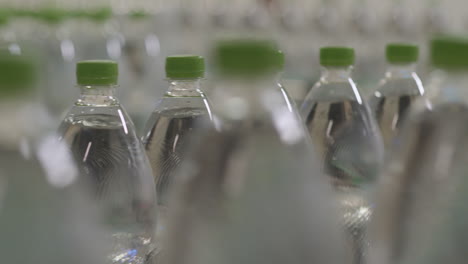 botellas de plástico llenas de agua mineral pura en un transportador en una moderna fábrica de llenado de agua con poca profundidad de campo