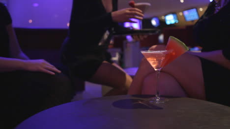 a waitress brings cocktails to 2 ladies on ladies night